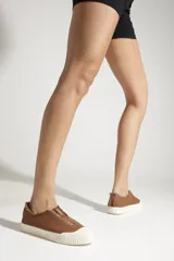 Sneaker slip-on Schutz color camel, confeccionada en lona con bordes deshilachados y suela de goma blanca con textura estriada en la puntera.