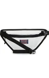 Riñonera transparente con bordes y cierre en color lila. Cuenta con el logo de la marca JanSport en el frente.