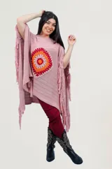 Poncho rojo de tejido artesanal con aplique central de crochet en forma de mandala con tonos amarillos, blancos y rojos. Presenta terminación con flecos en los laterales y diseño holgado.