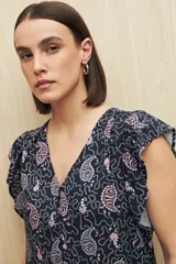 Blusa estampada con motivos de hojas en tonos beige y negro, con escote en V, botones al frente y volados en los hombros.