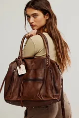 Bolso tote de cuero lavado negro con efecto gastado, interior amplio, bolsillos exteriores con cremallera, dos asas de mano y correa desmontable y regulable.
