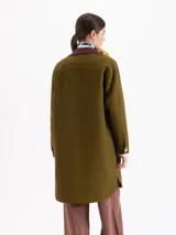 Tapado de largo a la rodilla en color verde oliva, confeccionado en panamá de algodón. Presenta un cuello de cuero con tachas y punteras metálicas, bolsillos plaqué con tapa y detalles de vivos en cuero.