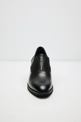 Zapato de cuero color beige, con taco de madera y suela dentada. Presenta un diseño slip-on con detalles de textura en relieve en los laterales y el empeine.