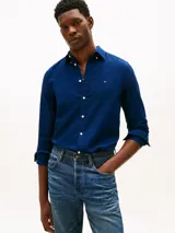 Camisa de corte slim color azul con textura dobby, manga larga, cuello abotonado y cierre frontal con botones blancos. Presenta el logo bordado de Tommy Hilfiger en el pecho.