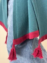 Chal de lana tejido con diseño de bloques de color gris, negro y crudo, con flecos borgoña en los extremos.