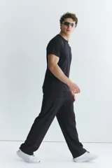 Pantalón deportivo negro de corte estándar y piernas rectas, confeccionado en tejido funcional ripstop con tecnología DryMove™. Cuenta con cintura elástica con cordón de ajuste oculto, bolsillos laterales con cierre y detalles perforados en las piernas.