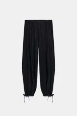 Pantalón negro de tiro alto con cintura elástica y bajo ajustado con lazada.