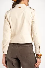 Chaqueta corta color beige de algodón, de inspiración militar con cuello mao y doble botonadura frontal con botones metálicos dorados.