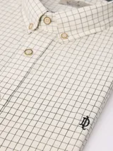 Camisa de manga larga con estampado de cuadros finos, cuello clásico con botones y cierre frontal. Presenta un bordado pequeño en la pechera y puños abotonados.
