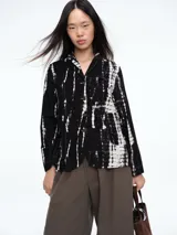 Chaqueta de corte recto y silueta cómoda, con cierre frontal de botones y bolsillos delanteros. Presenta un diseño estampado con efecto tie-dye en tonos negro y blanco.