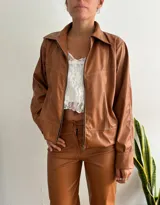 Campera marrón de cuero sintético con cierre frontal, cuello camisero y costuras decorativas en hilo blanco.