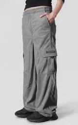Pantalon cargo de corderoy gris, de corte regular y diseño holgado. Cuenta con seis bolsillos, incluyendo bolsillos laterales tipo cargo con solapa y etiqueta decorativa.