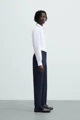 Camisa de manga larga para hombre, corte slim fit, con cuello italiano y cierre frontal de botonadura. Presenta un microestampado de cuadros pequeños en tonos blanco y celeste.