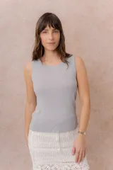 Musculosa de tejido fino con textura acanalada, color blanco, escote redondo y hombros anchos.