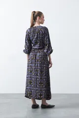 Vestido largo de silueta fluida con estampado abstracto en tonos azul, marrón y beige. Presenta escote en V con botones forrados y cintura elastizada. Mangas 3/4 abullonadas.