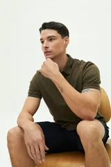 Remera polo verde militar con textura, corte regular, cuello con terminaciones en azul marino y logo estampado en el pecho.