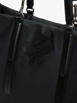 Cartera tote negra de Tommy Hilfiger, confeccionada en poliéster reciclado, con doble asa superior, compartimento principal y logo monograma bordado en el frente.