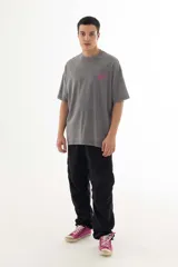 Remera gris con efecto acid wash, corte holgado y estampa pequeña en el pecho con diseño abstracto en color fucsia.