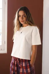 Remera blanca de algodón con cuello redondo y manga corta. Presenta un pequeño bordado de un pato en el pecho.