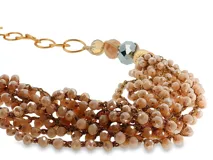Collar de múltiples hilos con cuentas de cristal facetado en tonos melocotón, complementado con cuentas decorativas grandes en tonos metálicos y neutros, y detalles dorados.