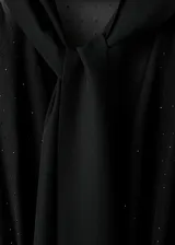 Mono largo color negro de diseño recto, con cuerpo superior transparente de manga larga, cuello en pico con fular incorporado y cierre delantero.