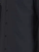 Camisa de manga larga color azul marino oscuro, de corte slim, confeccionada en algodón elástico mercerizado. Presenta cuello en punta, puños segados, bajo redondeado y un pequeño logo bordado de Calvin Klein en el pecho.