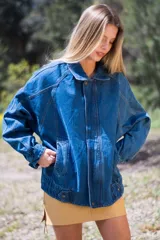 Campera de denim azul de corte oversize, con cuello, cierre frontal, bolsillos laterales amplios y ajuste en puños y bajo.