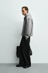 Sudadera gris de corte boxy fit con capucha y cierre frontal de cremallera. Confeccionada en tejido doble y compacto, cuenta con bolsillos laterales ocultos en la cadera y mangas largas con puños elásticos.
