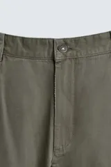 Pantalón de corte carrot fit confeccionado en tejido de algodón con estructura diagonal y efecto lavado. Presenta bolsillos frontales con bolsillo cerillero, bolsillos traseros de plastrón y cierre frontal con cremallera y botón.