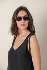Vestido corto de seda color gris oscuro, con escote redondo y tirantes anudados en los hombros. El calce es suelto y la tela es ligeramente transparente.