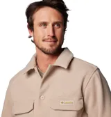 Campera tipo sobrecamisa Columbia de estilo retro, confeccionada en tejido de textura suave color beige. Presenta cierre frontal con botones, cuello clásico, dos bolsillos frontales con solapa y un anillo en D metálico en el bolsillo derecho. Incluye etiqueta de la marca en el bolsillo izquierdo.