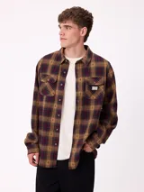 Camisa de manga larga confeccionada en franela de algodón, con diseño de cuadros en tonos verde y marrón. Presenta cuello clásico, cierre frontal con botones y dos bolsillos en el pecho con solapa.