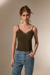 Body de breteles finos color blanco, con escote en V y detalle de encaje en el borde superior. Confeccionado en poliéster, presenta un diseño ajustado al cuerpo con cierre de broches en la parte inferior.