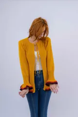 Saco de lana merino color mostaza, tejido a punto con detalle de volados en ruedo y puños. Tiene dos cierres frontales hechos en crochet a mano.
