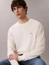 Sweater Calvin Klein de tejido de punto color blanco marfil, con cuello redondo, puños y bajo acanalados, y pequeño monograma CK bordado en el pecho.