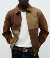 Chaqueta Marfinno de corte recto con diseño de bloques en tonos tierra, confeccionada en poliuretano con base de poliéster. Presenta cuello camisero estructurado, cierre frontal con zíper, mangas largas y forro interior con bolsillo funcional.