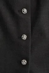 Top strapless entallado confeccionado en punto roma, con cierre frontal de botones decorativos tipo joya y corte ligeramente acampanado en la parte inferior.