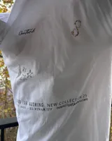 Remera blanca de algodón con cuello redondo y estampado con la frase "Good for nothing new collection est. 2001 el pinar city" y un pato con una botella de alcohol.