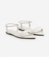 Sandalia plana Satinato de color plateado, con diseño metalizado, tira delantera fija y tira elástica en el tobillo. Cuenta con puntera fina.