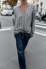 Blusa de manga larga con cuello redondo y escote en pico, cierre frontal con botones y diseño de rayas verticales.