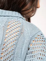 Sweater tejido de algodón color crudo, con cuello polo y escote en V. Diseño con ochos verticales en delantera, espalda y mangas, y punto abierto.