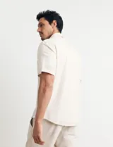 Camisa sport de manga corta, confeccionada en una mezcla de lino y algodón. Presenta cuello clásico, cierre frontal con botones de coco y un bolsillo aplicado en el pecho.