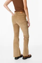 Pantalón de jean tipo pana color negro, de corte acampanado y tiro medio, con cierre frontal y bolsillos laterales.