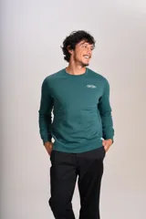 Buzo verde oscuro de cuello redondo, mangas largas con puños elásticos y pequeño estampado ovalado en el pecho.