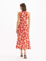 Vestido midi sin mangas con estampado floral en tonos rojos y celestes, cuello alto y detalle fruncido en el centro delantero.