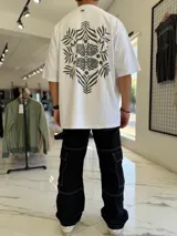 Remera oversize blanca con gran estampado en la espalda de diseño floral simétrico en tono oscuro. Cuenta con mangas cortas y calce holgado.