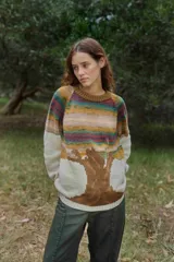 Sweater de tejido de punto con diseño artístico de un árbol en la parte inferior y franjas horizontales multicolores en la parte superior. Presenta cuello redondo, mangas largas y puños acanalados.