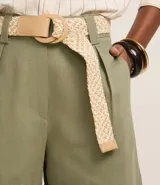 Short recto de cintura alta color crudo, confeccionado en viscolino, con trabillas en la cintura, pliegues y cierre tradicional. Incluye cinturón de rafia artificial con hebillas de argollas.