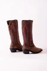 Bota texana de cuero negro con apliques de cuero marrón en los laterales y pespuntes en color crema. De caña media/alta y taco bajo. Diseño calado con motivos geométricos.