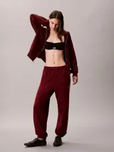 Jogger de felpa color bordó, de corte tapered y tiro medio, con cintura elástica y bolsillos laterales. Cuenta con puños ajustados en los tobillos y detalle del monograma de Calvin Klein en la pierna.